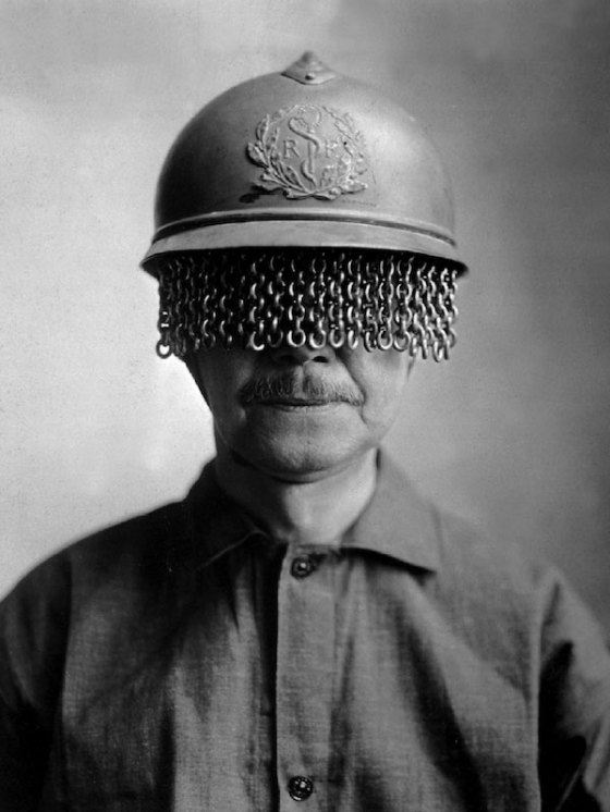 A man models a steel helmet covered with a built-on chain screen to protect a soldier's eyes from rocks, shells, and other fragments during World War I, 1918. It was created by E J Codd Company of Baltimore, Maryland. War Department photo. (Photo by Interim Archives/Getty Images)