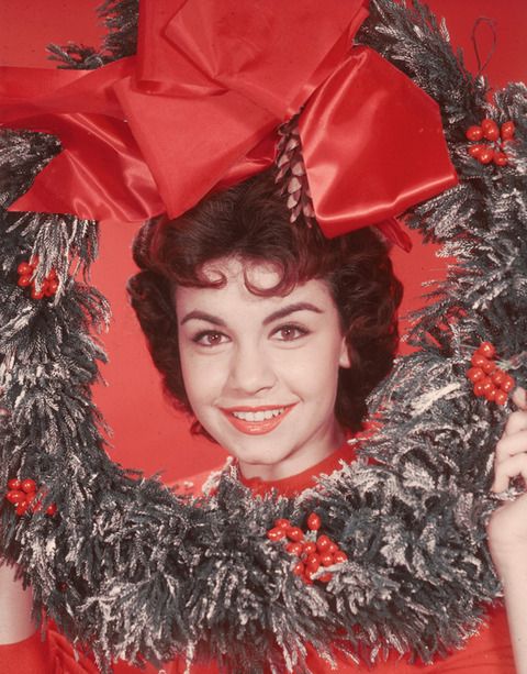 Headshot portrait of American actor and singer Annette Funicello, posing with her head encircled by a decorative Christmas wreath, circa 1955. There is a large ribbon above her head. (Photo by Hulton Archive/Getty Images)