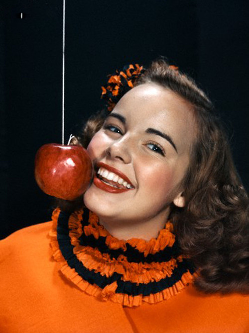 01 Jan 1940 --- 1940s 1950s smiling young woman wearing halloween costume bobbing for apple on a string --- Image by © Camerique/ClassicStock/Corbis